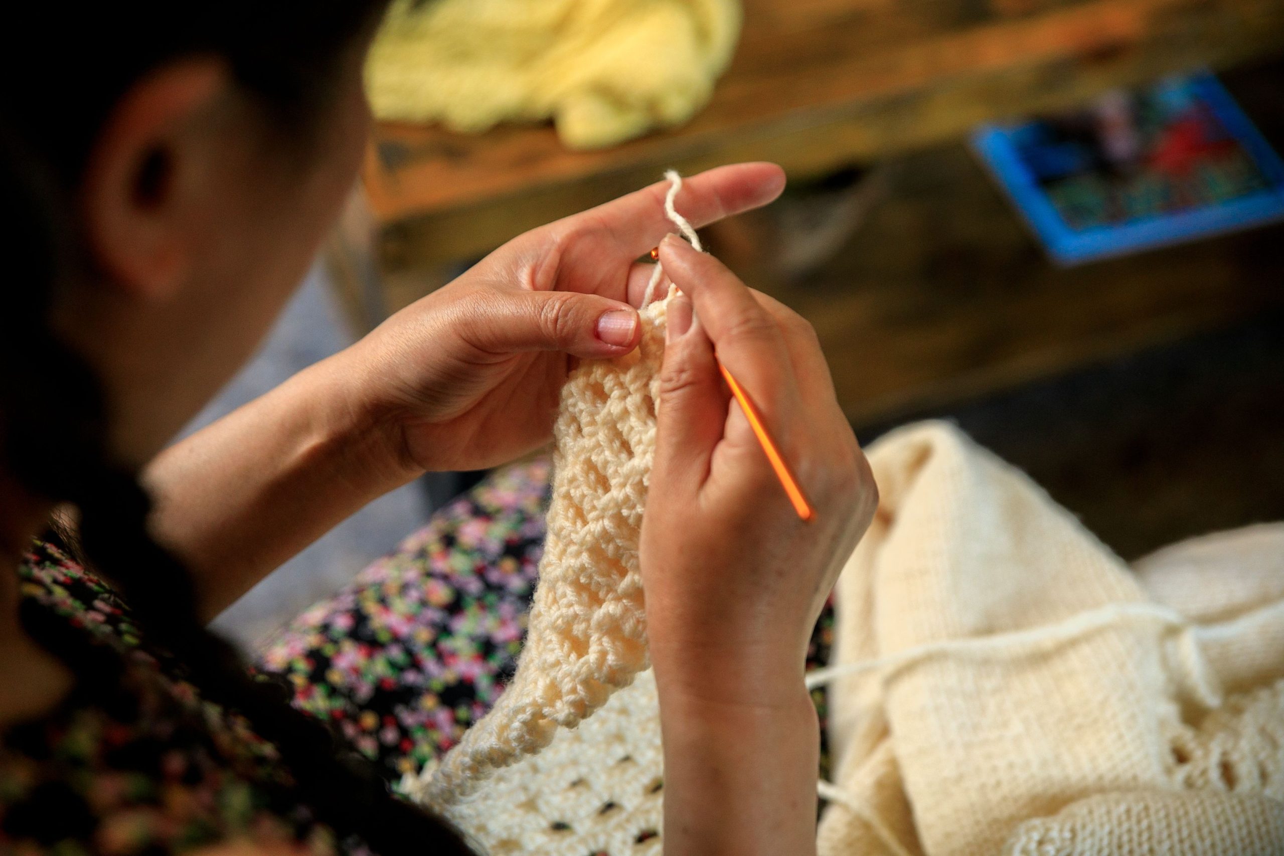 A woman skillfully crochets with wool in a cozy indoor setting.